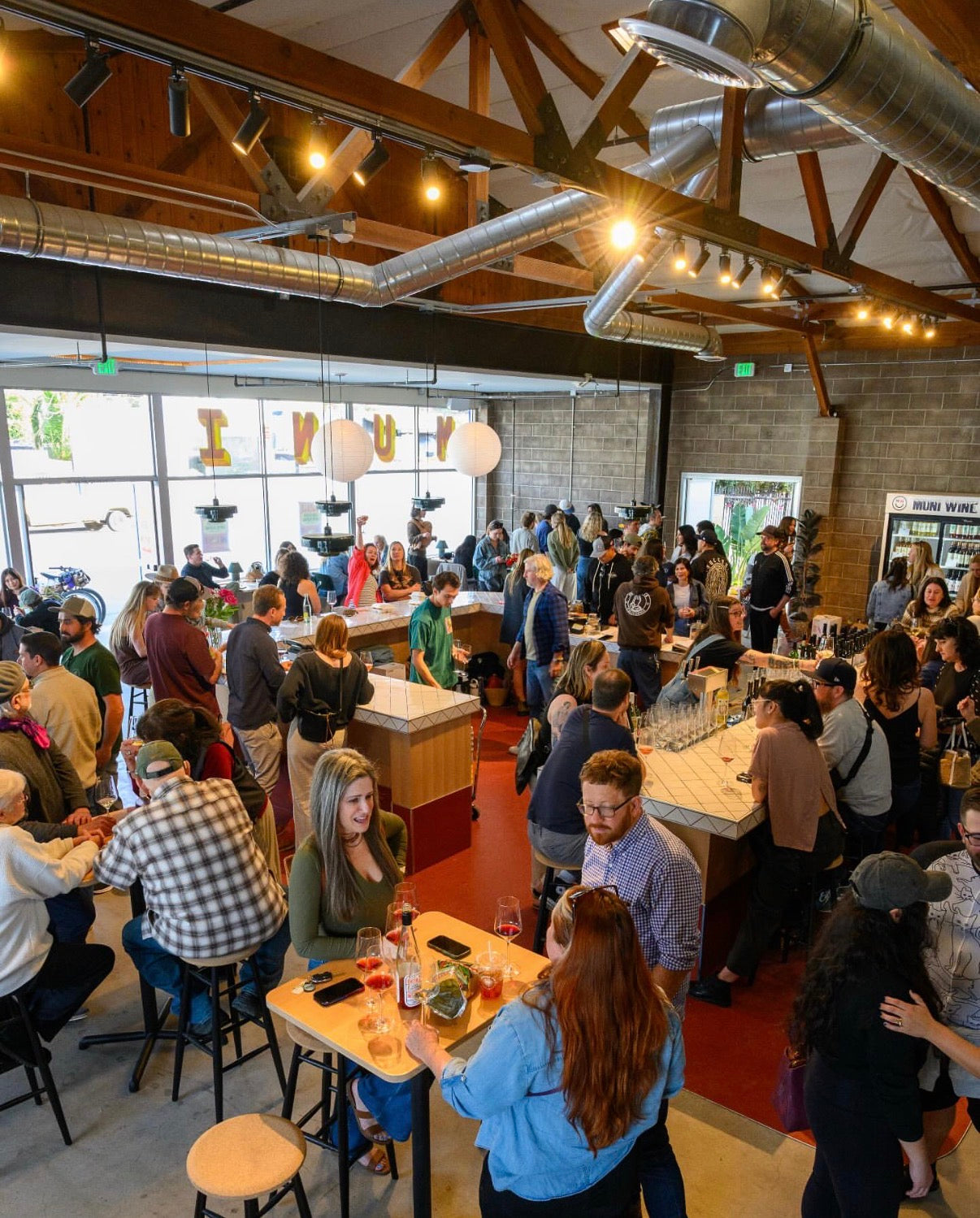 Guests enjoying wine and conversation at a busy Municipal Winemakers tasting room event