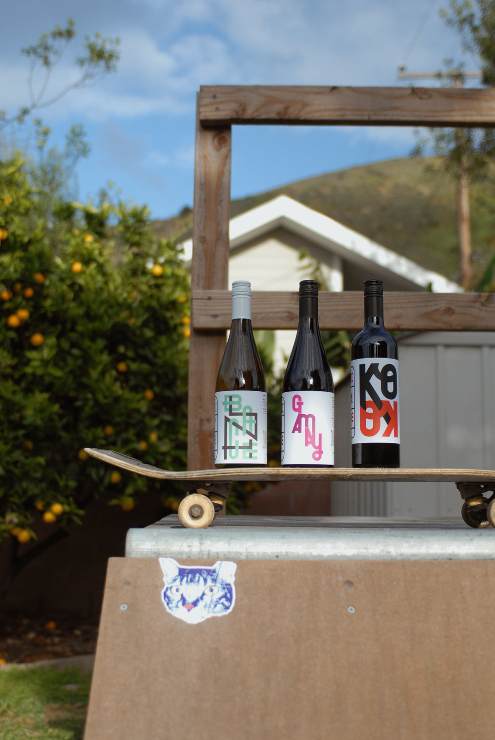Three Muni wine bottles standing on a skateboard outdoors