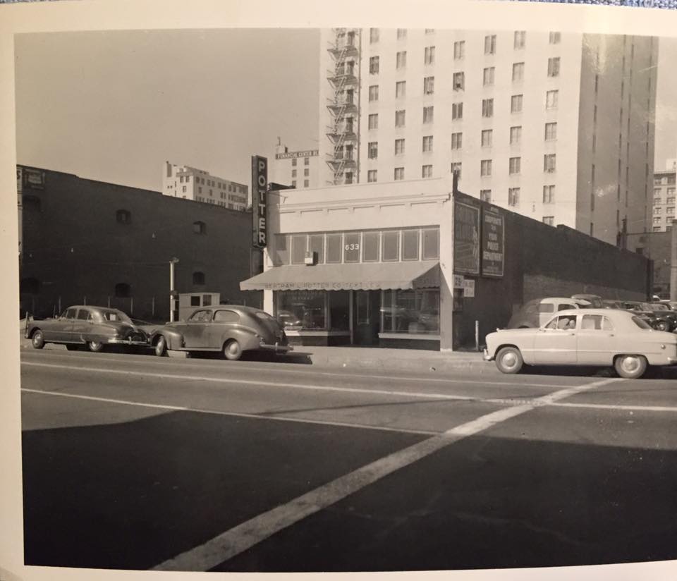 A storefront with a vertical Potter sign and cars parked along the street.